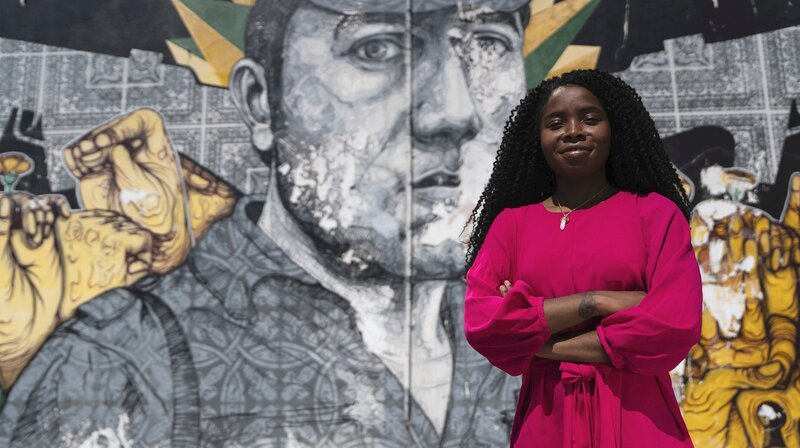 Mafalda Fernandes vor einem Graffiti des Revolutions-Helden Salgueiro Maia.; hr-fernsehen NELKEN FÜR DIE REVOLUTION, Ein Film von Brigitte Kleine, am Donnerstag (10.10.24) um 23:00 Uhr. Mafalda Fernandes vor einem Graffiti des Revolutions-Helden Salgueiro Maia. © HR/​Joël Hess, honorarfrei – Verwendung gemäß der AGB im engen inhaltlichen, redaktionellen Zusammenhang mit genannter HR-Sendung bei Nennung „Bild: HR/​Joël Hess“ (S2). HR/​Pressestelle, Tel: 069/​155⁠–⁠4954 – Bild: HR/​Joël Hess