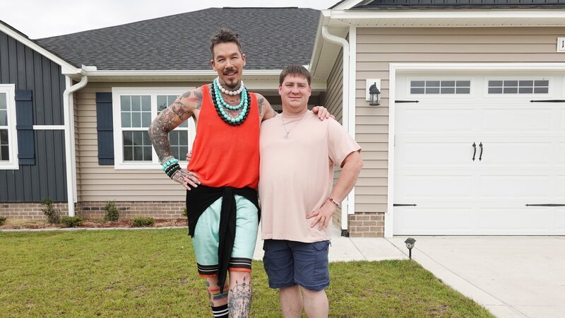 Host David Bromstad (left) poses for a picture with lottery winner Benjamin Haynes (right) outside of House 2, mid pine passage – Bild: HGTV US /​ Warner Bros. Discovery, Inc.