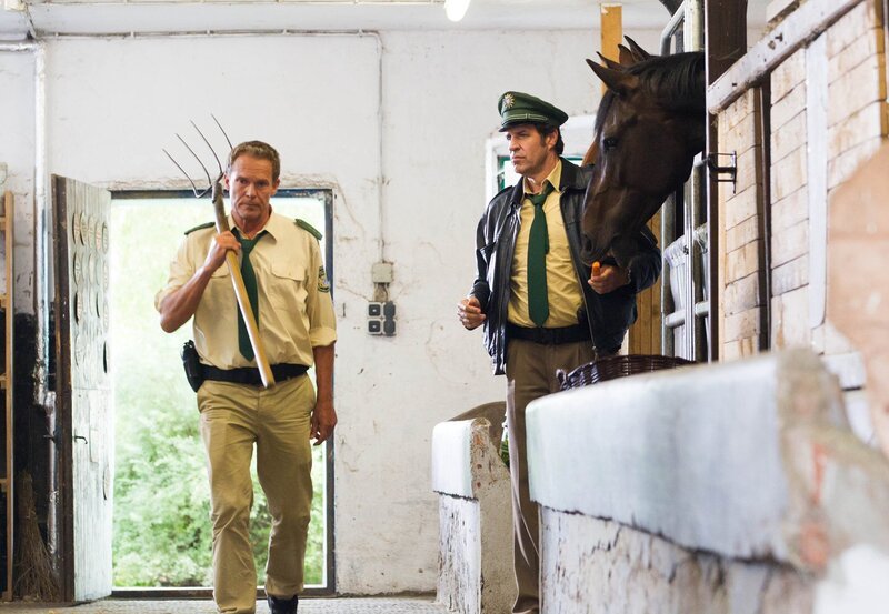 Hubert (Christian Tramitz, links) und Staller (Helmfried von Lüttichau) schauen sich noch mal im Stall von Hermann Meixner um. Hubert nimmt die Mistgabel als Beweisstück mit. – Bild: ARD/​TMG/​Chris Hirschhäuser