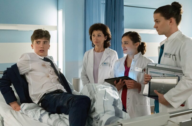 Tom (Tilman Pörzgen, r.) und Rebecca (Milena Straube, 2.v.r.) kümmern sich unter Prof. Karin Patzelts (Marijam Agischewa, 2.v.l.) Anleitung um den schüchternen Abiturienten Lukas Reimers (Florian Burgkart, l.), der nach der Abifeier betrunken und mit einer Hundebissverletzung im JTK landet. – Bild: ARD/​Jens Ulrich Koch