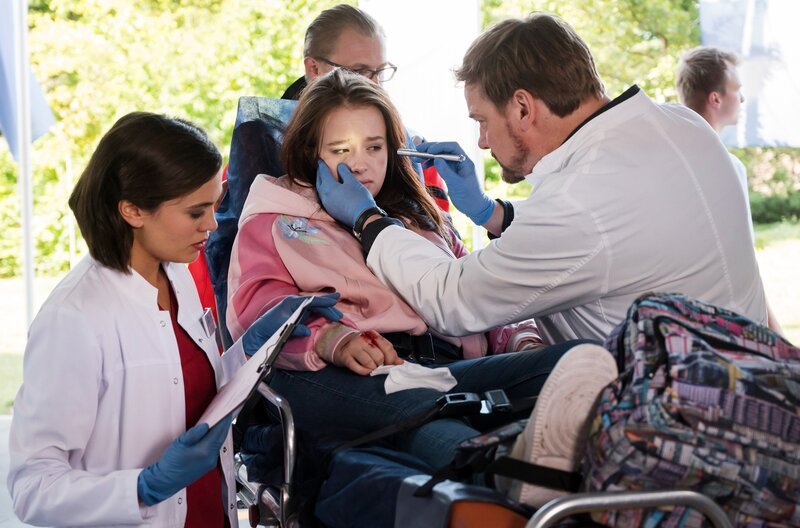 Malou Meisner (Fine Sendel, M. mit Komparse, h.) kommt mit einer Alkoholvergiftung und einer Handverletzung ins Klinikum. Marc Lindner (Christian Beermann, r.) und Rebecca Krieger (Milena Straube, l.) nehmen sie auf. – Bild: ARD/​Jens Ulrich Koch