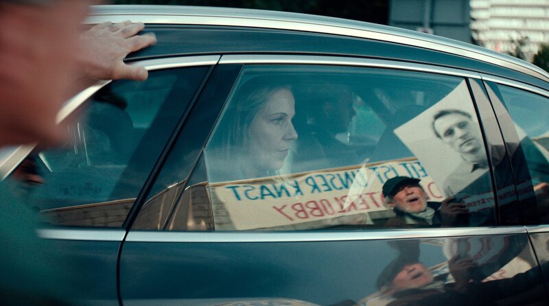 Ministerin Hammerschmidt (Cordula Stratmann) wird von Demonstranten belagert. – Bild: WDR/​Studiocanal