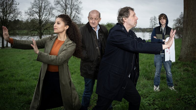 Die Region wird von einer Serie rätselhafter Einbrüche heimgesucht und dann geschieht auch noch ein Mord. Währenddessen wird Privatdetektiv Georg Wilsberg (Leonard Lansink, 2.v.l.) von einer besorgten Mutter beauftragt, herauszufinden, wo sich ihr Teenager-Sohn Nils (Julius Gause, r.) tagsüber herumtreibt. Wie sich herausstellt, hat Nils einen brisanten Verdacht, wer den Mord begangen haben könnte. Die Suche führt Wilsberg in ein Jugendzentrum, welches das Mordopfer und Nils verbindet und wo Wilsberg sich mit den Zukunftsängsten junger Menschen konfrontiert sieht. Währenddessen probieren sich Juristin Dr. Tessa Tilker (Patricia Meeden, l.) und Ekki Talkötter (Oliver Korittke, 2.v.r.) in Übungen zur Gelassenheit. – Bild: ZDF und Thomas Kost