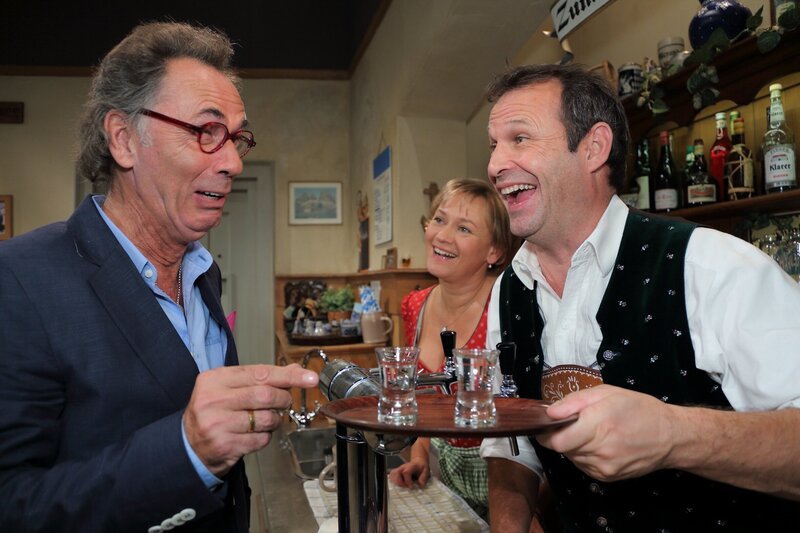 Nicht jedes Nordlicht verträgt den bayerischen Klaren. Jörg Knuppe jedenfalls hat damit zu kämpfen … Von links: Jörg Knuppe (Hugo Egon Balder), Monika (Michaela Heigenhauser) und ihr Mann Matthias Birkmoser (Markus Neumaier). – Bild: BR/​Foto Sessner