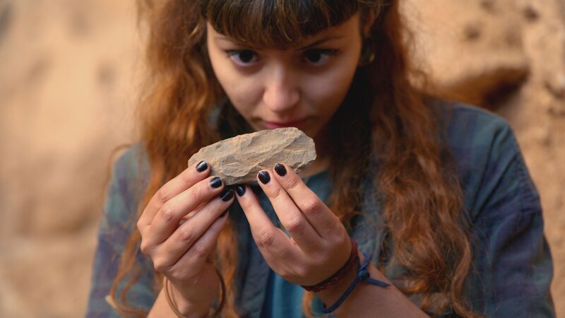 In der marokkanischen Grotte des Pigeons entdeckt die Archäologie-Doktorandin Meryem Benerradi Werkzeuge und Muschelperlen, die der Homo sapiens als Schmuck benutzt haben könnte. – Bild: THE HISTORY CHANNEL /​ ZDF Digital