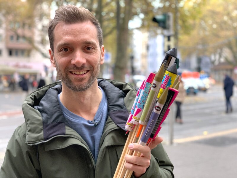 Feuerwerk gehört für viele zu Silvester wie Sekt und Raclette. Nach zwei Pandemie-Jahren mit Verkaufsverbot für Raketen, Böller und Co. darf das neue Jahr jetzt wieder mit einem Knall begrüßt werden. Was Feuerwerksfans und vor allem die finanziell gebeutelten Hersteller freut, kritisieren andere wegen Verletzungsgefahr, Feinstaubbelastung und Müll. Geht Feuerwerk auch umweltfreundlicher, werden Raketen und Co. jetzt teurer und können Drohnenflugshows eine Alternative sein? Daniel Aßmann beleuchtet in „Ausgerechnet -Feuerwerk“ beide Seiten. Er besucht u.a. Deutschlands größten Hersteller für Pyrotechnik und erfährt, was zwei Jahre Stillstand für die Branche bedeutet haben. – Bild: WDR