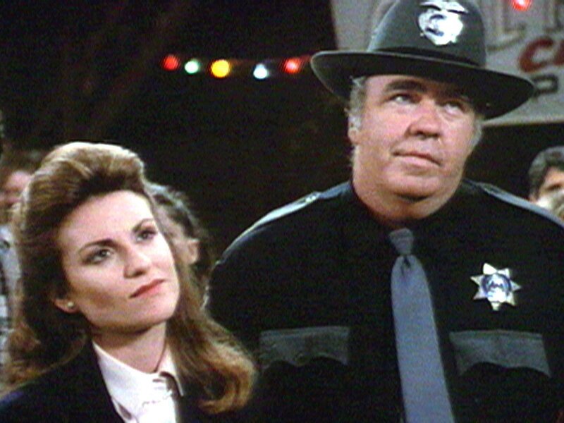 Molly (Megan Mullally) wird von Sheriff Tate (Hoyt Axton) wegen Hausfriedensbruch verhaftet. – Bild: Warner TV Serie