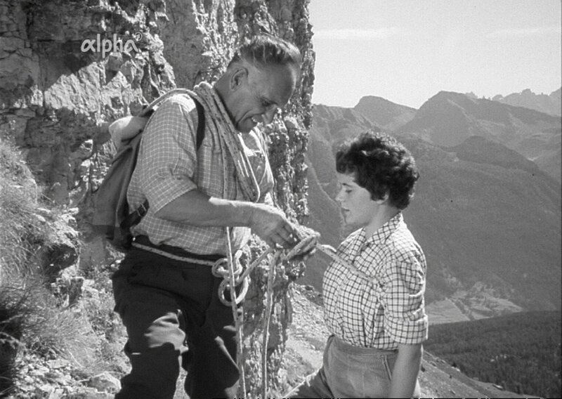Männer und Frauen getrennt: Auf zwei verschiedenen Wegen gelangt man ans Ziel, auf den Gipfel der Rotwand im Rosengartengebiet in den Dolomiten. Der legendäre Bergsteiger und -führer Luis Trenker führt in dieser Reportage zwei Kletterer, Günther Johne und Winfried Ender, in die Finessen der Klettertechnik ein und schickt sie die Steilwand hinauf, während die Dame, Trenkers Nichte Helga Franzelin, mit Trenkers Begleitung von Bozen auf der leichteren Südseite aufsteigt. Wer ist als erster da? – Bild: BR