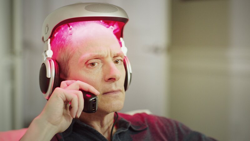 Ashley talking on his cellphone will wearing his hair growing machine on his head. – Bild: Discovery Communications, LLC.