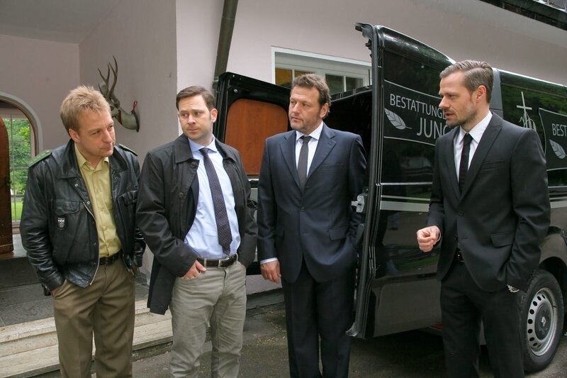 Kommissar Königs (Mark-Alexander Solf, 2.v.l.) erster Fall führt ihn und Polizist Michi Mohr (Max Müller, l.)  zu Bestattungsunternehmer Jung (Martin Muliar, 2.v.r.; Sven Waasner, r.). – Bild: ZDF und Christian A Rieger