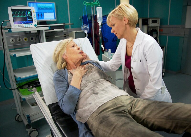 Kathrin Globischs (Andrea Kathrin Loewig, rechts) demenzkranke Mutter Eva (Heidemarie Wenzel) wird in die Notaufnahme eingeliefert. Aus ungeklärten Gründen hat sie in ihrem Zimmer im Pflegeheim einen Brand verursacht und sich dabei eine Rauchvergiftung zugezogen. – Bild: MDR/​Wernicke