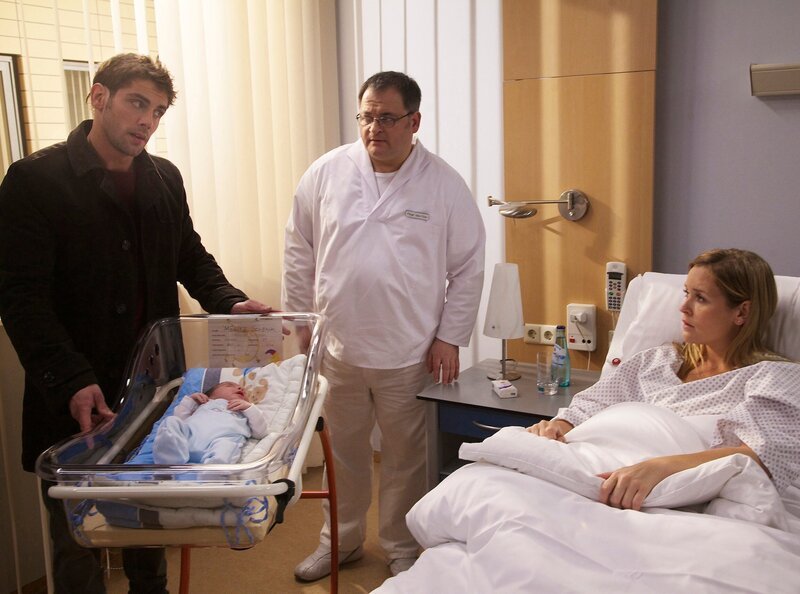 Als Dr. Niklas Ahrend (Roy Peter Link, links) nach Jasmin Schenk (Judith Hoersch, rechts) sieht, fällt ihm auf, dass es ihrem Neugeborenen Kind gar nicht gut geht. Obwohl er kein Arzt an der Sachsenklinik ist, schnappt er sich das Baby und will es sofort untersuchen. – Bild: MDR/​Saxonia/​Wernicke