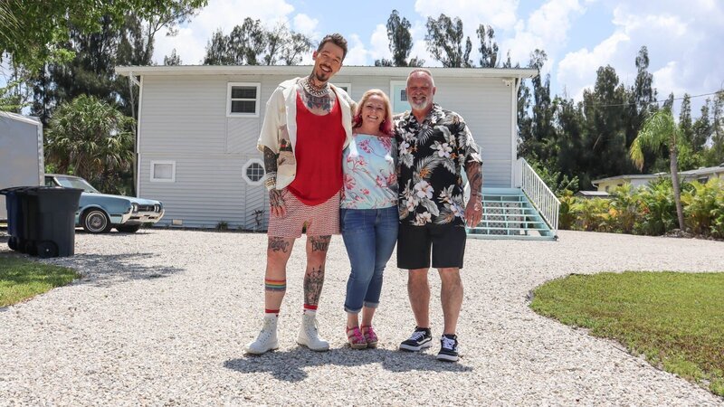Host David Bromstad, Christine Gustafson, and Ken Gustafson, pose for picture outside of House 2, Nutgrass Nursery, as seen on My Lottery Dream Home, Season 16. – Bild: Warner Bros. Discovery, Inc.