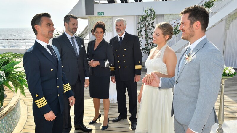 Zur Überraschung von Hanna Liebhold (Barbara Wussow, 3. v. l.) und Staff-Kapitän Martin Grimm (Daniel Morgenroth, 3. v. r.), präsentieren Hochzeitsplaner Tom Cramer (Jan Hartmann, 2. v. l.) und Kapitän Max Parger (Florian Silbereisen, l.) ein weiteres Brautpaar: Ina Rossi (Nicola-Rabea Langrzik, 2. v. r.) und Tino Möller (Felix Kreutzer, r.). – Bild: ZDF und Dirk Bartling