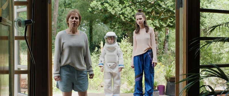 Tom (Theo Kretschmer), seine Schwester Nina (Lilli Lacher) und Mutter Vera (Eva Löbau) kommen bei den Großeltern zu Hause in Lunau an. Tom trägt dabei seinen Astronautenanzug und Helm. – Bild: Leitwolf Filmproduktion GmbH