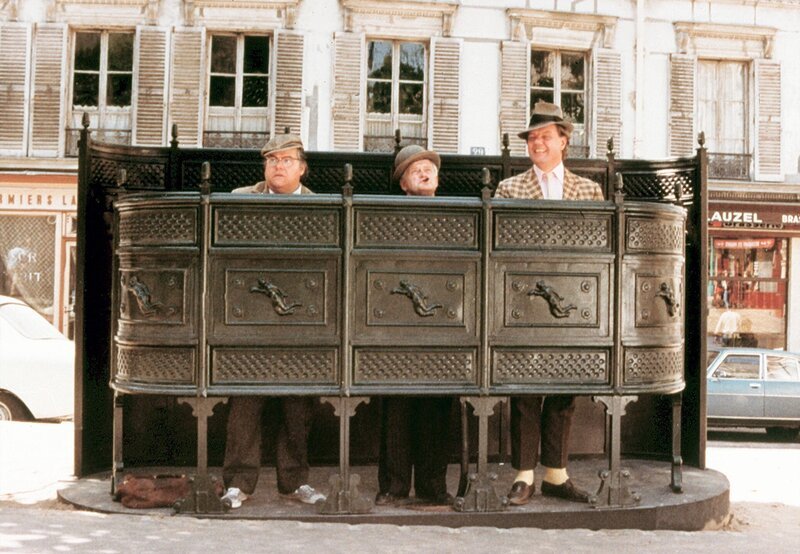 Nach einer langen Fahrt als blinde Passagiere eines Bierkutschers verschaffen Egon und seine beiden Kumpane sich nach ihrer Ankunft in Paris erst einmal Erleichterung. – Bild: MDR/​DEGETO