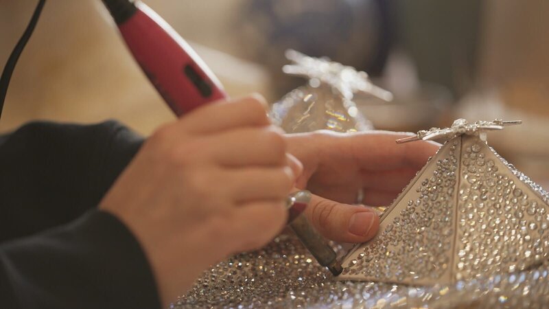 Mit ruhiger Hand werden funkelnde Kostüme Stein für Stein verziert. – Bild: WELT