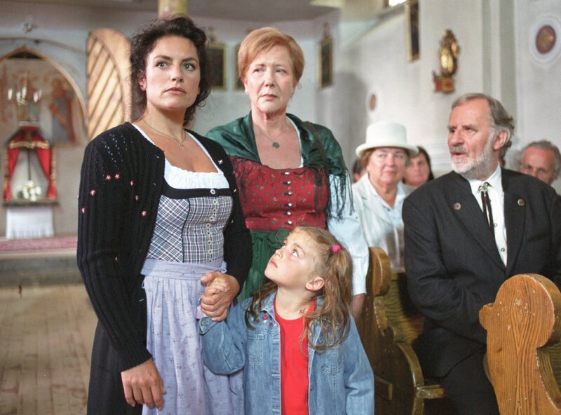 Die Almbesitzerin Anna (Christine Neubauer, li.), ihre Mutter Zensi (Veronika Fitz, 2.v.li.) und ihre Tochter Elise (Ronja Forcher, vorne) werden von der Dorfgemeinschaft gnadenlos ausgegrenzt. – Bild: ARD/​Degeto/​Marco Orlando Pichler