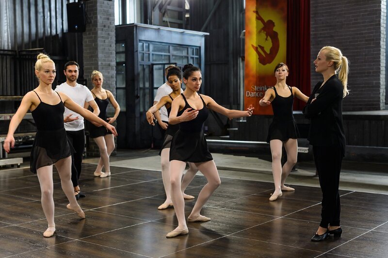 Während Isabelle (Ania Niedieck, r.) die Schüler genüsslich auf ein knallhartes Jahr an der SDF vorbereitet, ist Raquel (Yara Hassan, M.) fest entschlossen, sich von Isabelles Schikanen nicht provozieren zu lassen (l. Jenny Bach, 5.v.l. Jennifer Dessin-Brasching, Komparsen) – Bild: RTL Passion
