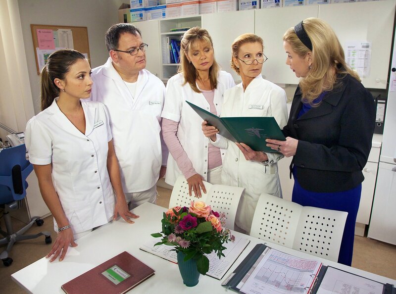 Sarah Marquardt (Alexa Maria Surholt, re.) stellt im Schwesternzimmer ihr Konzept zur Effizenzsteigerung der Pfleger und Schwestern vor. – Bild: MDR/​Saxonia/​Wernicke