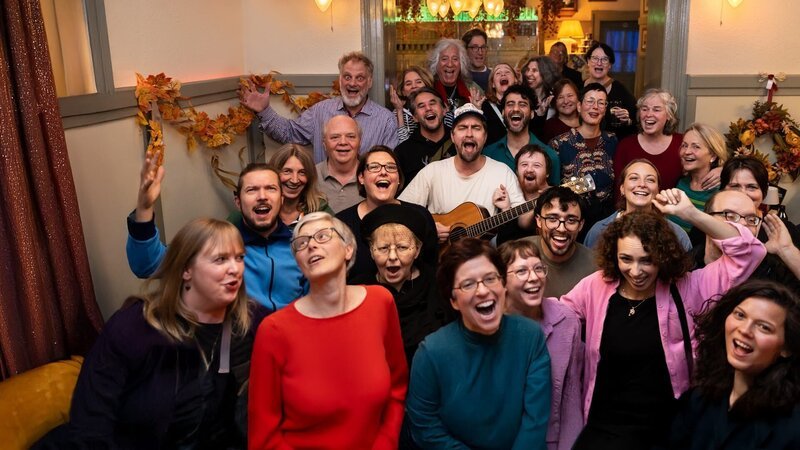 In Mannheim trifft sich der Thekenchor dort, wo andere den Tag ausklingen lassen. Keine Notenblätter, keine steifen Regeln – dafür Lachen, Biergläser, Popmusik. Gründer David (Mitte mit Gitarre) will zeigen, dass Singen gelebte Demokratie und Inklusion sein kann: laut, offen, für alle. Aber wie politisch kann ein Chor sein, der vor allem Spaß machen will? – Bild: Arthur Bauer (über ifage) In Mannheim trifft sich der Thekenchor dort, wo andere den Tag ausklingen lassen. Keine Notenblätter, keine steifen Regeln – dafür Lachen, Biergläser, Popmusik. Gründer David (Mitte mit Gitarre) will zeigen, dass Singen gelebte Demokratie und Inklusion sein kann: laut, offen, für alle. Aber wie politisch kann ein Chor sein, der vor allem Spaß machen will? – Bild: Arthur Bauer (über ifage)