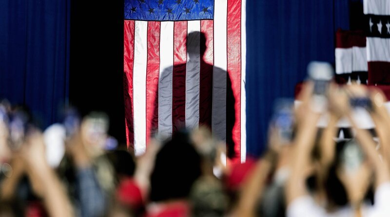 Donald J. Trumps Schatten hinter der amerikanischen Flagge, als er sich auf seinen Auftritt bei einer „Keep America Great“-Kundgebung im Santa Ana Star Center vorbereitet, Rio Rancho, USA. – Bild: rbb/​IMAGO/​ZUMA Press Wire