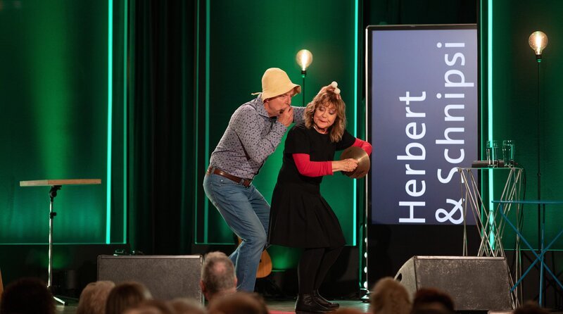 Seit 40 Jahren stehen sie gemeinsam auf der Bühne: Herbert & Schnipsi alias Hanns Meilhamer und Claudia Schlenger-Meilhamer gehören zu Bayerns bekanntesten und beliebtesten Komödianten. Im aktuellen Programm „Zeitreise mit Schlaglöchern“ werfen sie einen Blick zurück auf ihre Karriere und holen dabei persönliche Lieblingsstücke noch einmal auf die Bühne. – Bild: BR/​Sabrina Wanninger