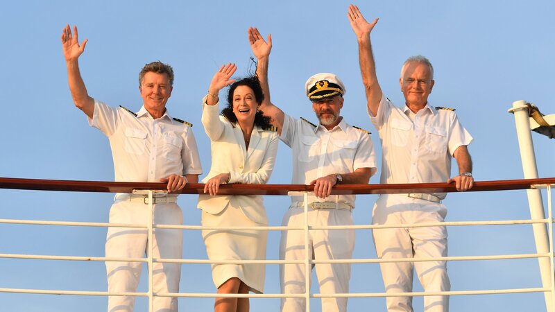 Unter der Führung des Ersten Offiziers Martin Grimm (Daniel Morgenroth, 2.v.r.) sticht das „Traumschiff“ in See. Gemeinsam mit Hanna Liebhold (Barbara Wussow, 2.v.l.), Dr. Sander (Nick Wilder, l.) und Oskar Schifferle (Harald Schmidt, r.) bereitet er den Gästen an Bord eine unvergessliche Reise nach Sambia. – Bild: ZDF und Dirk Bartling