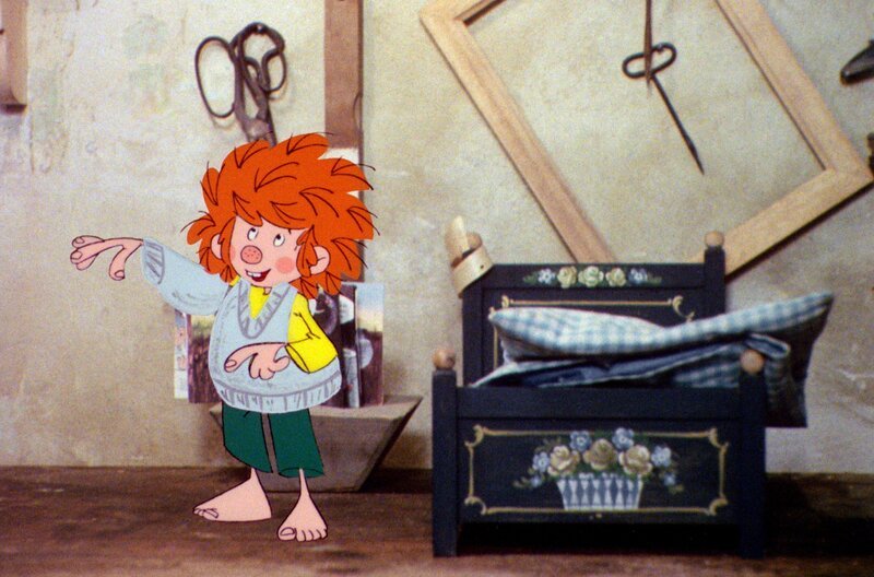 Pumuckl friert schrecklich, weil es in der Werkstatt so kalt ist. Die nette Frau Schröder strickt ihm einen kleinen Pullover. – Bild: BR/​Infafilm GmbH/​Original-Entwurf „Pumuckl“-Figur: Barbara von Johnson