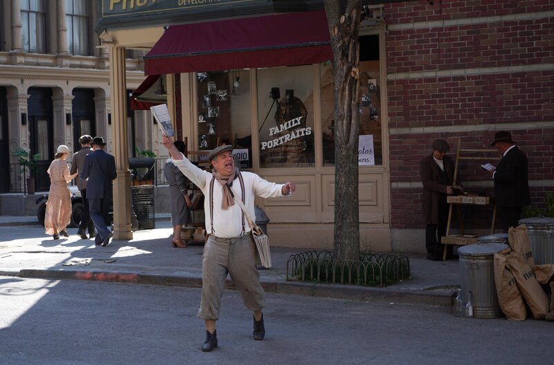 Der Zeitungsjunge (Paul Sedlmeir) bringt schreckliche Nachrichten. Die Börse ist zusammengebrochen. Die Welt steht am Abgrund. Aber jede Krise ist nur eine dornige Chance. – Bild: ZDF und Dea Atanasova