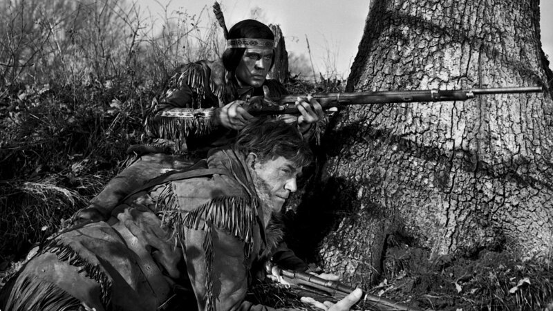 Unkas (David Alexandru, oben) und Lederstrumpf (Hellmut Lange) beobachten das Lager der Huronen, in dem die entführten Mädchen gefangen gehalten werden. – Bild: ZDF und Skocrowsky/​Deropa-Franco-London