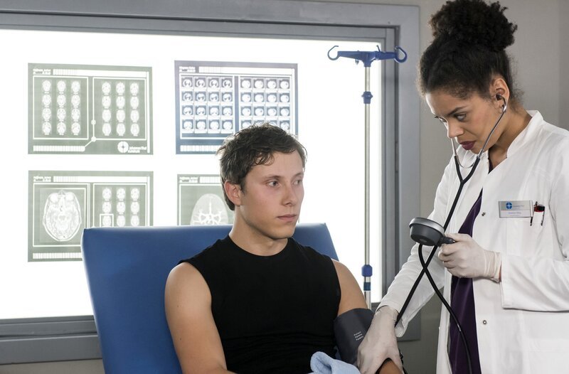 Vivi (Jane Chirwa, rechts) nimmt die ersten Untersuchungen an Chris Lewandoswksi (Jan-David Bürger) vor. – Bild: ProSiebenSat.1 Media SE /​ Jens-Ulrich Koch
