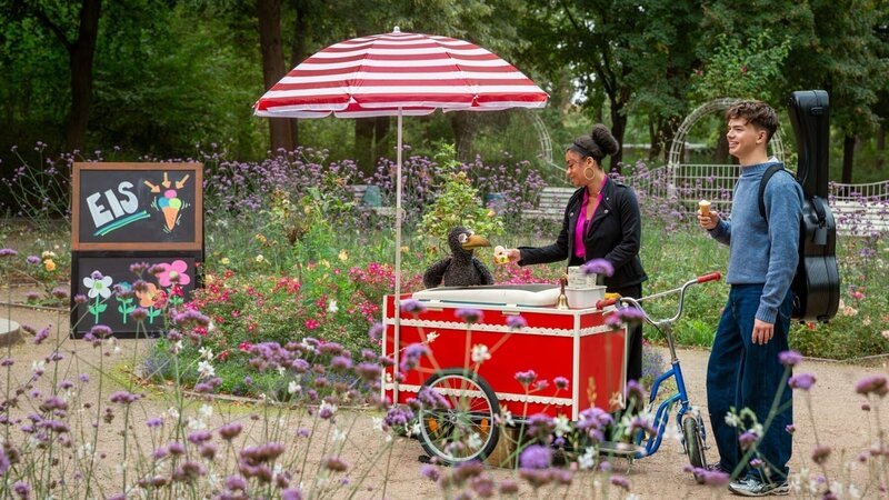 Zum Glück trifft Rabe Rudi (Lennart Morgenstern) Benno Panhans. Mit dessen fantastischem Gitarrenspiel ist das fehlende Geld für ein Eis schnell eingesammelt. – Bild: ZDF/​Adam Kaiser-Lynch