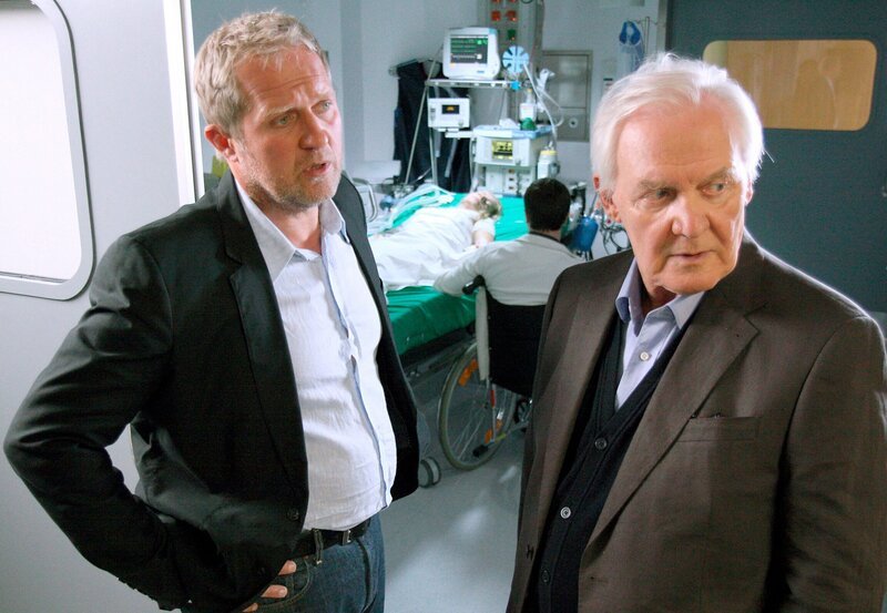 Nach dem schrecklichen Autounfall liegt Claudia (Susanne Michel, im Hintergrund) im Koma. Thomas (Harald Krassnitzer, links) verdächtigt den behandelnden Arzt einer unzureichenden Behandlung. Er teilt Gottfried (Wolfgang Hübsch, rechts) mit, wie kritisch Claudias Zustand ist. – Bild: ARD/​ARD/​ORF/​Milenko Badzic