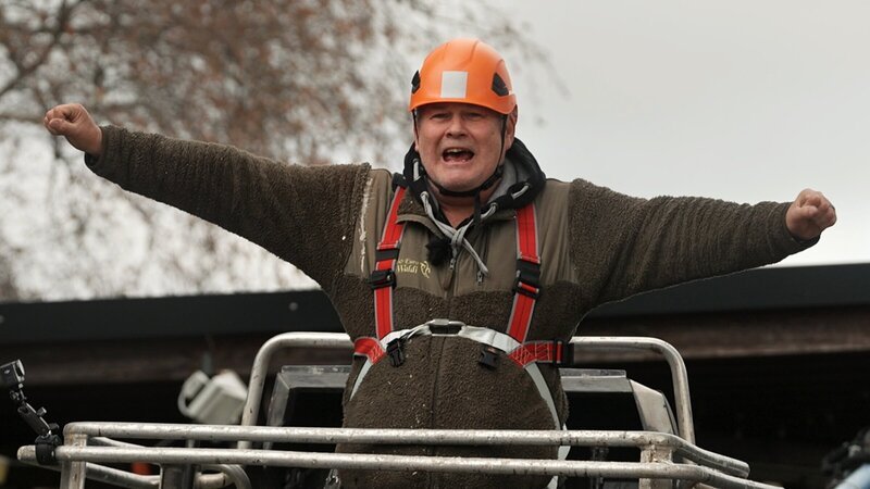 Waldi lässt sich mit einem Kran hochfahren, um einen Weihnachtsbaum zu schmücken. – Bild: ZDF und Warner Bros. Deutschland