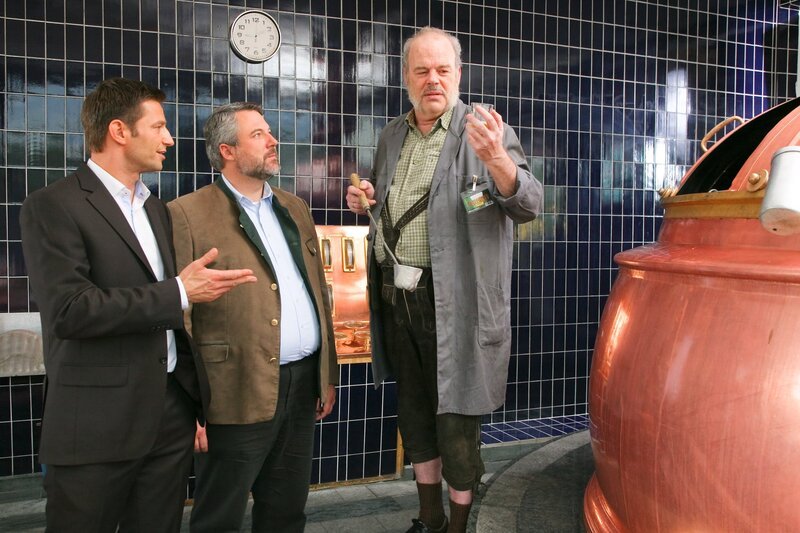 Die Rosenheim-Cops (Igor Jeftic, l.; Dieter Fischer, m.) ermitteln und verdächtigen Josef Moosbach (Andreas Pegler, r.) seinen Ex-Chef aus Rache getötet zu haben. – Bild: ZDF und Christian A. Rieger