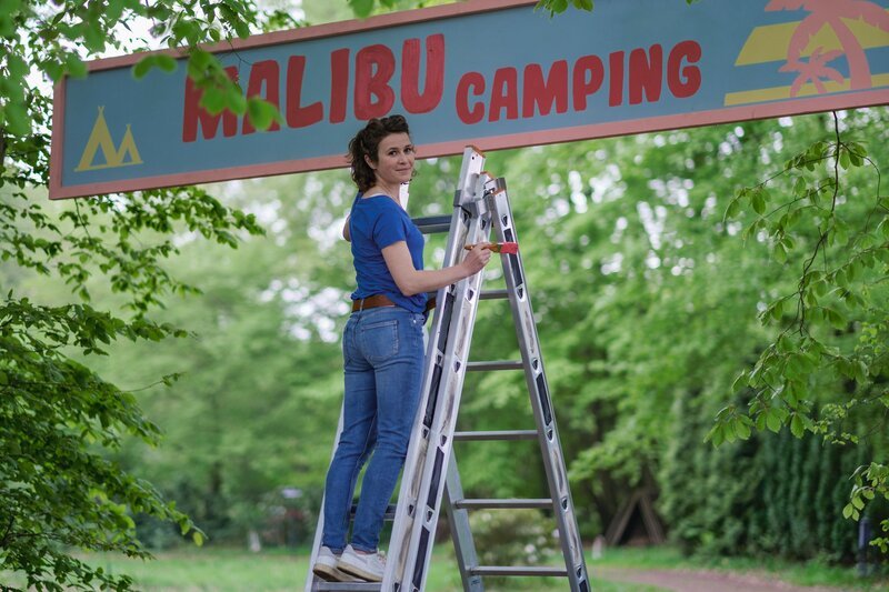 Jantje (Karla Nina Diedrich) verpasst dem Eingang von „Malibu Camping“ einen neuen Anstrich. – Bild: ZDF und Manju Sawhney