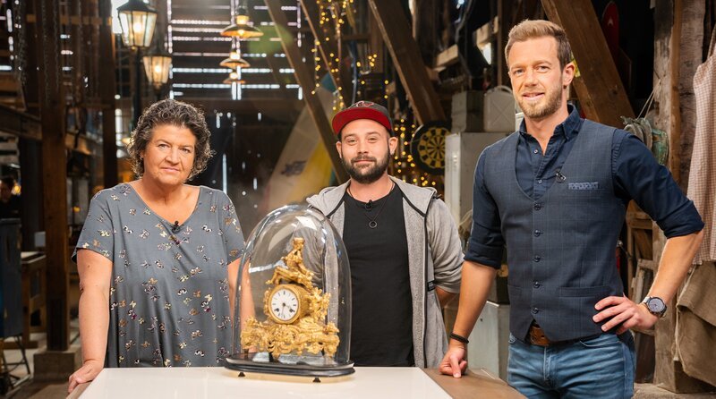 Ute Andok mit ihrer Kaminuhr und Uhrmacher Jan Böck sowie Moderator Arndt Reisenbichler – Bild: SWR/​av medien