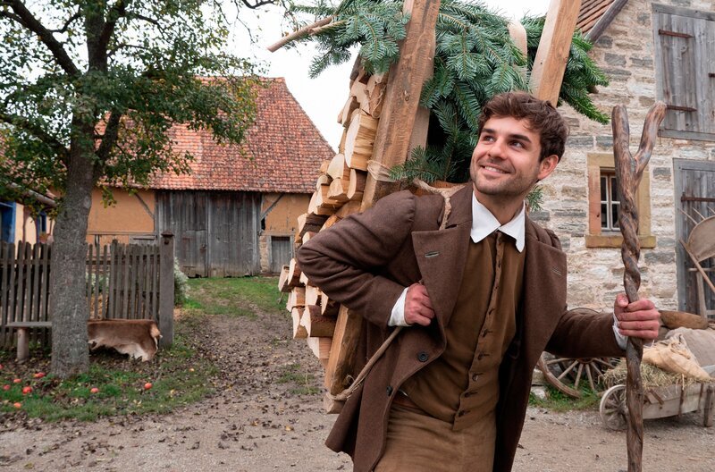 Hans (Lucas Reiber) trägt Holz. – Bild: BR/​Michael Boxrucker