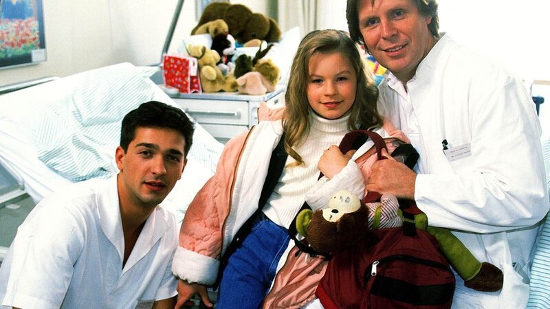 Umsorgt von Dr. Stefan Frank (Sigmar Solbach, r.) und Julian (Andreas Elsholz) fühlt sich das Waisenkind Iris (Jana Kilka) wohl. – Bild: MG RTL D /​ Elke Werner
