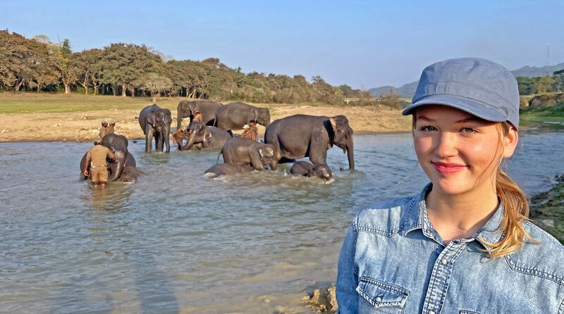 Nina begleitet indische Mahuts und ihre Elefanten beim täglichen Flussbad. – Bild: BR/​Text und Bild Medienproduktion GmbH & Co. KG/​Marcella Müller