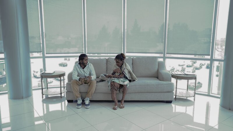 Charmaine Sahadeo and son Osiris James sitting side-by -side in hospital waiting area, Charmaine holding phone talking to her son – Bild: Warner Bros. Discovery, Inc. or its subsidiaries and affiliates. All rights reserved.