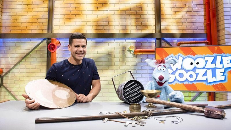 Woozle (re.) ist Erfinder und Wissenschaftler – und er ist ein vorlautes, blaues Beuteltier mit einer Vorliebe für alles, was explodieren kann. Gemeinsam mit seinem besten Freund moderiert er ein Wissensmagazin für Kinder. Um einem Thema näherzukommen, hat Woozle aber sehr eigene Wege. Immer ist er am Tüfteln, Erfinden und Sachensprengen. Gemeinsam mit Simón (li.) geht er heute dem Thema Archäologie näher auf den Grund. – Bild: Annette Etges/​SUPER RTL