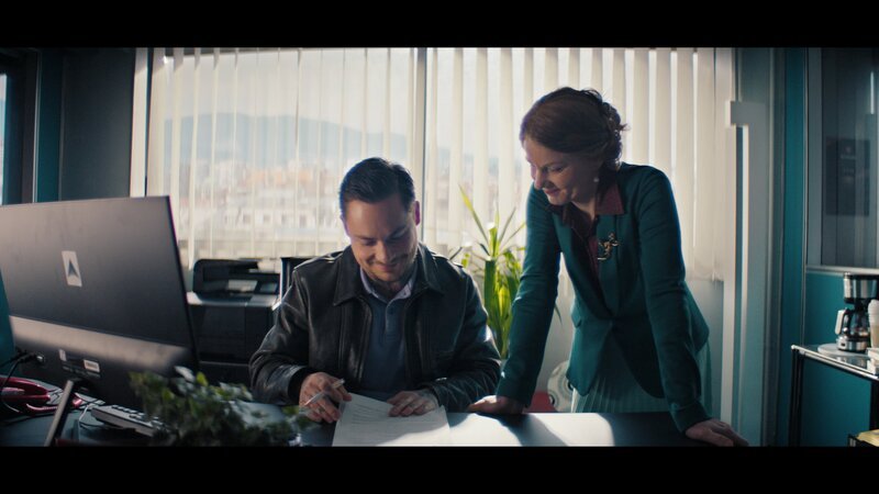 Niki Ignatov (Ferdinand Lehmann, l.) bekommt von Radka Ignatova (Jana Kozewa, r.) seinen OneCoin-Vertrag. – Bild: ZDF und Felix Poplawski