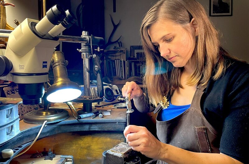 Waffengraveurin Sarah Wolske graviert eine Gürtelschnalle mit einer Punze. Sie hat das Gravieren in Österreich gelernt. – Bild: SWR/​Manuel Hollenweger