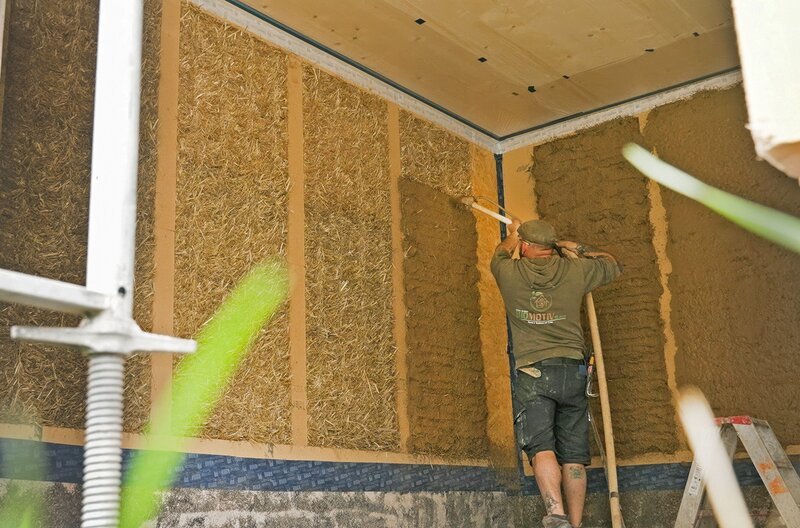 Die Wände des Strohballenhauses werden mit Lehm verputzt, damit sie atmen können. – Bild: SWR/​Dirk Schwarz
