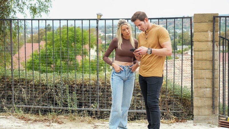 Tarek El Moussa and Heather El Moussa looking at his phone outside, as seen on The Flipping El Moussas, Season 2. – Bild: Warner Bros. Discovery, Inc. or its subsidiaries and affiliates