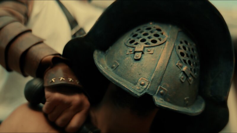 Marcus Atilius, ein Gladiator, der zum ersten Mal antritt, hält sein Schwert an den Hals des erfahrenen Gladiators Hilarus. – Bild: Dash Pictures /​ Antoan Ivanov