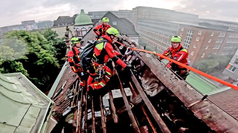 Einsatz in 20 Metern Höhe: Bei einem Dachstuhlbrand bereiten die Höhenretter die Sicherungen für ihre Kollegeninnen und Kollegen vor. – Bild: NDR/​TV News Kontor