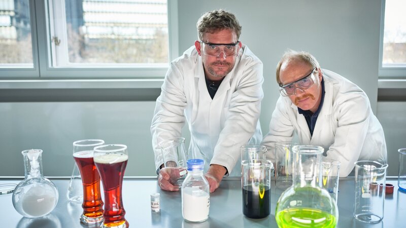 Die „Grenzgänger“ Sebastian Bezzel und Simon Schwarz in einem Chemielabor im Deutschen Museum. – Bild: Bernd Schuller /​ BR, Film Five GmbH